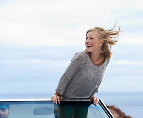 Happy, blue sky and convertible car with woman on road trip for travel, vacation or holiday in...