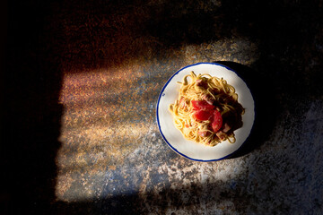 Homemade pasta (spaghetti) with tomatoes and sausages in plate in the rays of sunlight. Top view, flat lay, overhead, from above
