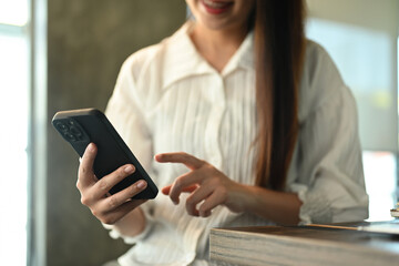 Happy young woman typing massage and communicating online on mobile phone