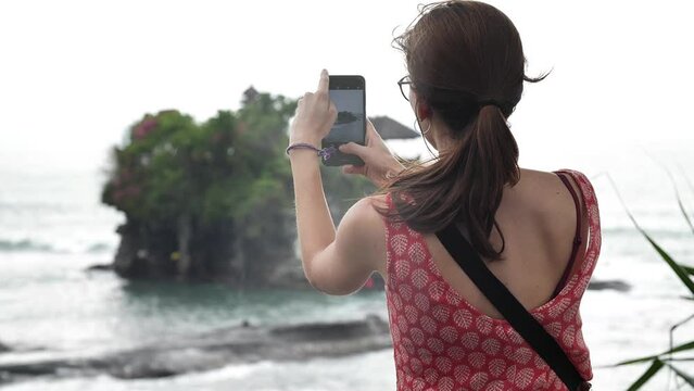 High definition slow motion footage of woman taking a picture with her mobile phone at Tanah Lot island temple, Bali, Indonesia.
Medium angle, parallax movement.