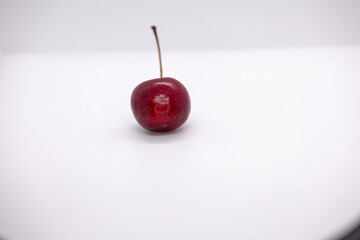 A single cherry on isolated white background shot using external flash, high quality photo