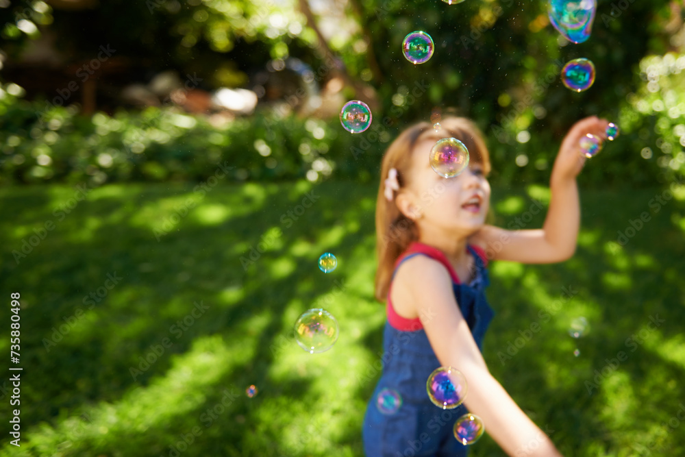 Wall mural Child, bubbles and garden grass for playing in summer sunshine in backyard for holiday, carefree or happy. Kid, girl and youth in California in outdoor nature or fun for vacation, weekend or game