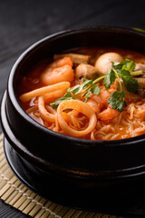 Korean food. seafood soup, salmon, eel, shrimp. on a black wooden background.