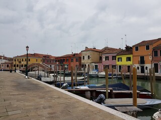 Canal, boats and small houses in Murano island, Venice on a cloudy afternoon