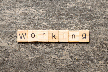 Fototapeta premium WORKING word written on wood block. WORKING text on cement table for your desing, concept