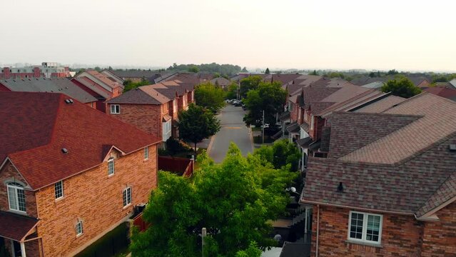Drone flyover capturing townhouses in suburban area, dynamic perspective on countryside real estate. Perfect for showcasing townhouse living, blending suburban tranquility with modern townhouse design