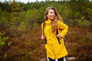 Pretty woman carrying a backpack in the forest  in the autumn season. Traveler enjoying nature. Concept of trekking, active lifestyle. Adventures.