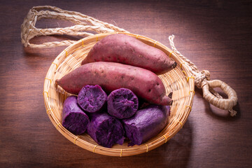 Purple potato in basket on wooden background, Japanese Purple Sweet Potato on wooden Background.