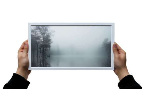 Person Holding Up a Picture of a Foggy Lake. A person holding a photograph depicting a foggy lake, showcasing the mist-covered water and surrounding landscape.