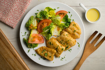 Battered white fish served with a tomato salad.