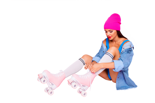 Attractive girl in stockings on roller skates ties up the shoelaces isolated on bright pink background