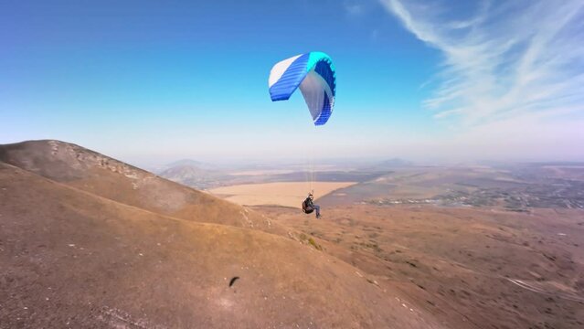 Filmed on a sports FPV quadcopter. A paragliding athlete flies on a sunny day next to a low mountain. Aerial view Adrenaline Concept, Drone Shot