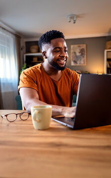 Young African American man sitting at home using laptop for video call.