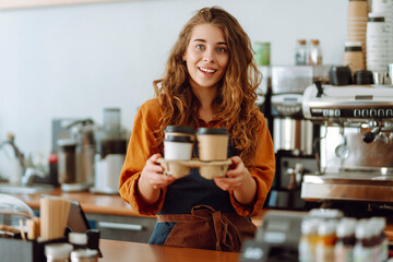 Portrait of  young barista woman serving coffee with a big smile. Takeaway food.