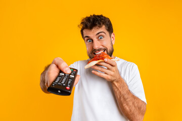 man enjoys slice of pizza while pointing remote control, studio