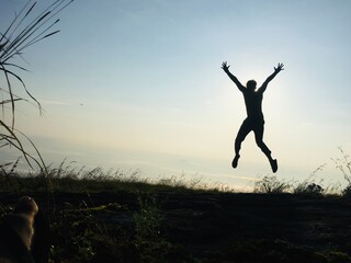 A young man jumping for joy on a mountain at sunset