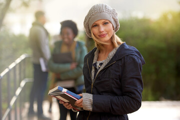 Closeup, winter and university student with book in outdoor on campus, happy and smile with support and care. Education, college with notes to prepare for exam, assessment and texbook to study.