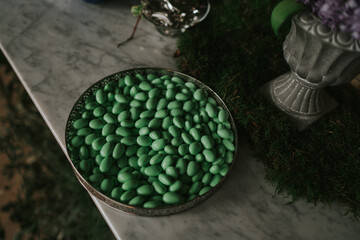 Confitería verde en placa de metal grabada sobre mesa de mármol blanco. Detalle de una boda...