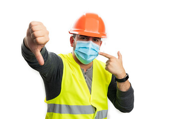 Constructor pointing at medical mask making thumb-down gesture