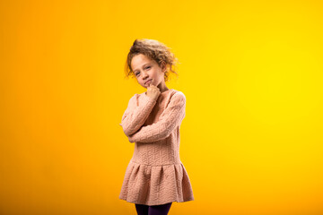 Sad girl holding cheek with hand feeling disappointment over yellow background.