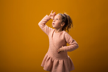 Child girl holding hand over eyes and looking attentively far away. Curiosity and waiting concept