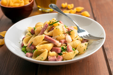 Piatto di deliziosa pasta con pisellini e prosciutto cotto, cibo italiano 