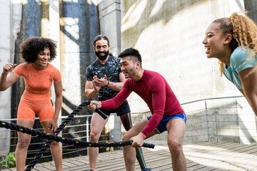 Multiethnic group of friends exercising with battle ropes and cheering each other