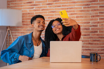 Multiethnic couple using a smartphone makes each other smile at home, a Latino boyfriend and an...