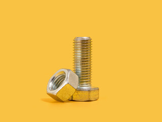 Metal bolt and nut on a yellow background. Ready for home renovation.