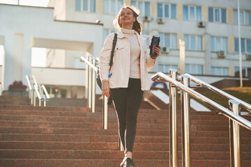 With water bottle. Young female student in casual clothes is outdoors