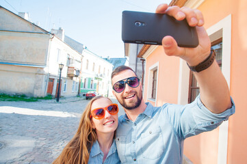 Catching the bright life moments. Beautiful young loving couple taking selfie with smart phone and smiling while traveling by Europe.