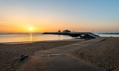 Dawn breaks over La Guirra Beach, Caleta de Fuste, casting a peaceful golden glow across the...