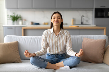 Relaxed young european woman practicing meditation on sofa