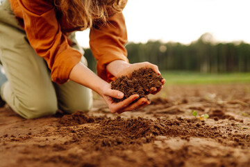 Woman Hands touching soil on the field and checking soil health before growth a seed of vegetable...