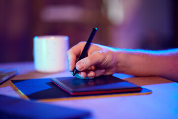 Male hand drawing on digital drawing pad in vibrant, illuminated workspace. Content creator and...