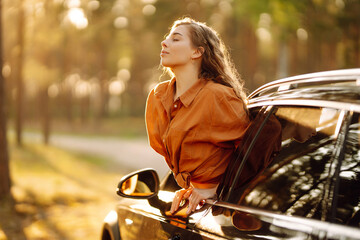 Happy woman leaning out of car window on summer road trip travel vacation.