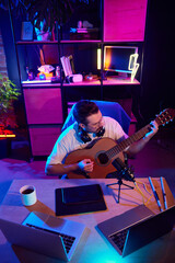 High angle view portrait of focused man in glasses producing acoustic melodies in colorful, illuminated workspace. Concept of youth people with social media and smart working, lifestyle, online. A