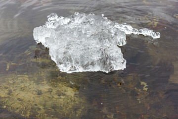 a piece of wet ice floats in the spring ice drift river close-up