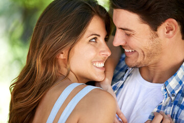 Fototapeta premium Closeup of a young couple loving in the park, and standing in the summer sun under the tree. Cheerful, bonding outdoor and romantic partners affectionate and playful smiling on vacation in nature