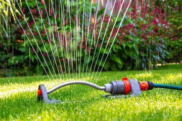 Close up of a lawn sprinkler in garden during a dry hot summer - 735976428