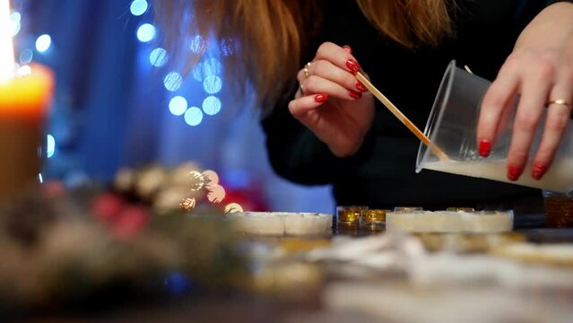 A woman carefully pours epoxy resin into a mold from a glass. A creative atmosphere prevails around her. High quality 4k footage