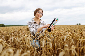 Naklejka na ściany i meble Woman agronomist working in grain field and planning income of harvest. Female examining and checking quality control of produce wheat crop. Agriculture, gardening or ecology concept.