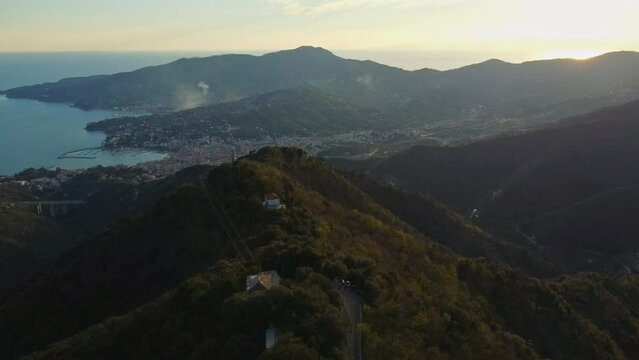 drone vista delle colline in Liguria. Sul fondo Rapallo. Mare e montagne al tramonto.
