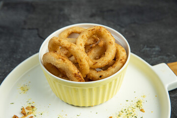 Onion rings on white plate on dark background