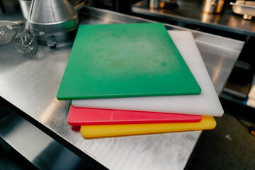 In the kitchen of a restaurant there are kitchen boards of different colors on the table for...