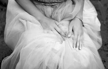 Black and white photo of women's hands on an elegant tulle light skirt. Femininity concept.