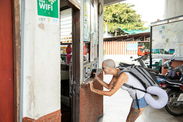 Mid age woman Solo traveller, is at a ticket office in a bus station in northern Thailand, she is using her phone to but bus tickets.