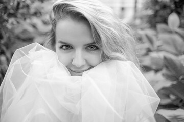 A black and white close-up portrait of a girl with a smile and a white tulle skirt, looking at the...