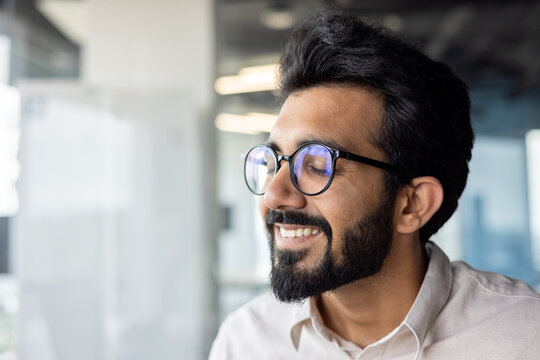 Close-up photo of satisfied and happy young indian man in glasses and shirt, closed eyes and resting, relaxed daydreaming