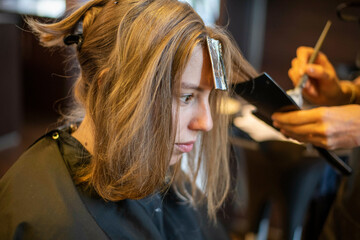Attractive blonde model having her hair done. Relaxing hair cut by professional stylist while she colours and sets her hair with highlights